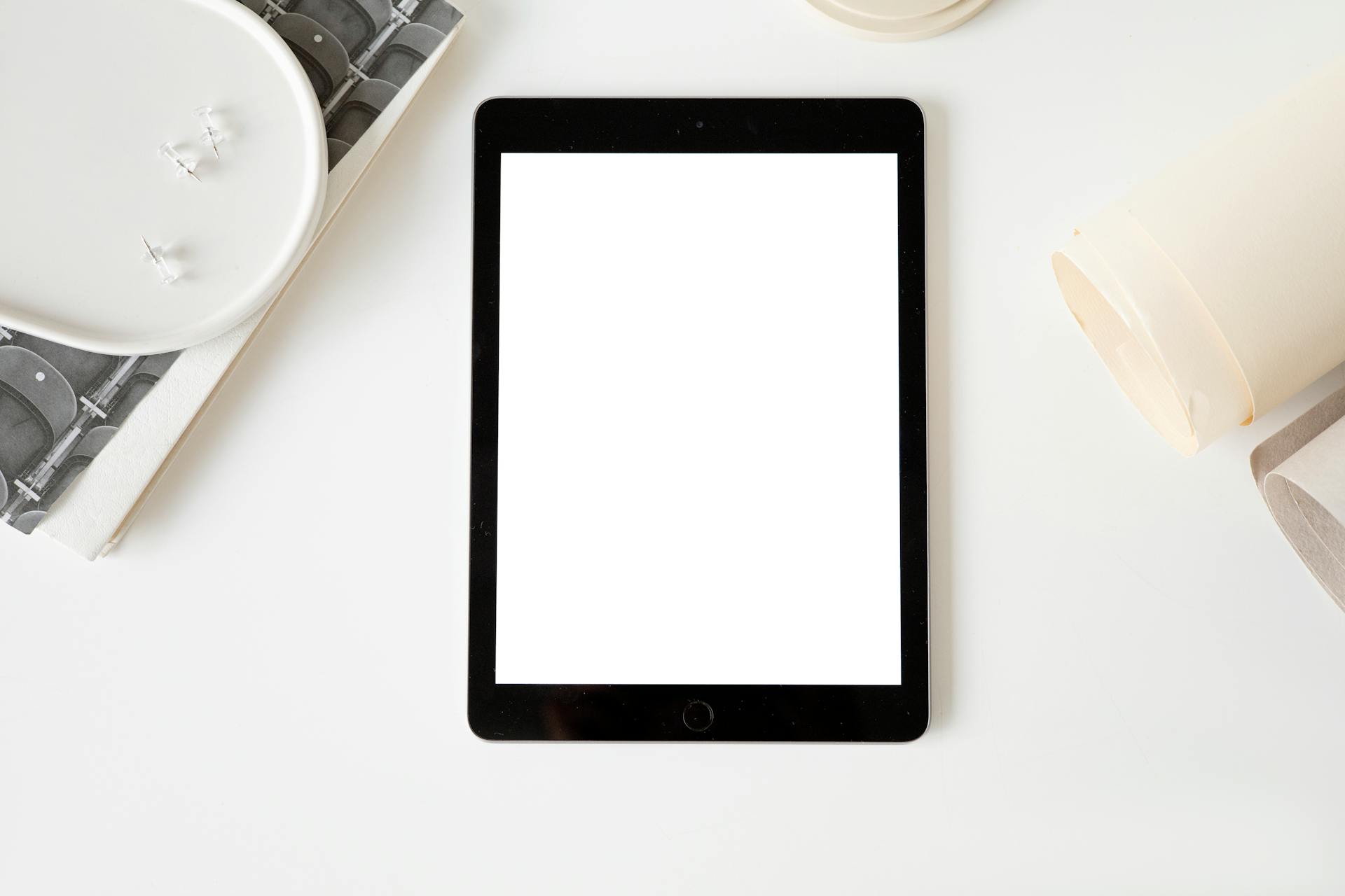 Tablet with blank screen on a minimalist white desk, ideal for mockup designs.