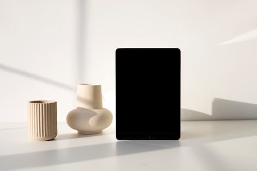 Stylish minimalist tablet mockup alongside modern ceramic vases in soft lighting.