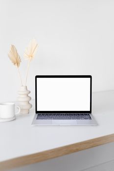Modern minimalist workspace with a laptop featuring a blank screen, ideal for mockups.