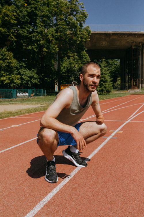 Free A determined male athlete with a prosthetic crouches on an outdoor track, ready to race. Stock Photo