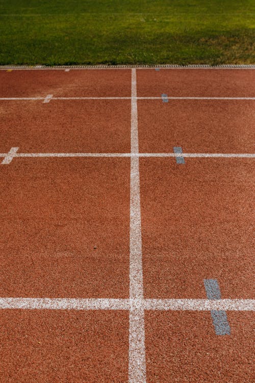 Abstract Shot of an Orange Running Track Surface with Marked Lines, and Lawn