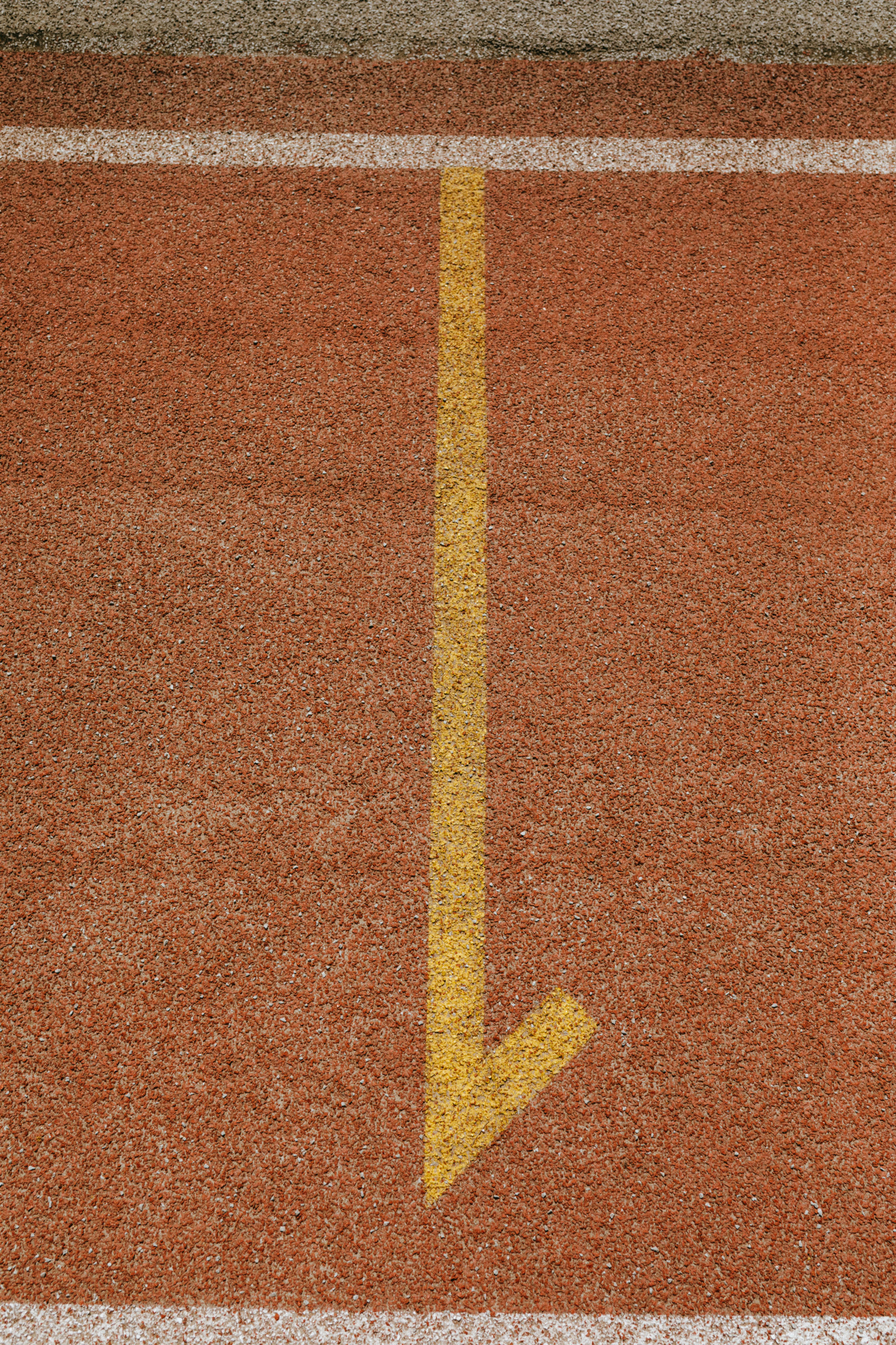 Vertical shot of a track with a yellow arrow indicating lane direction.