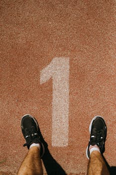 Runner ready at the starting line on a red race track, number one visible.