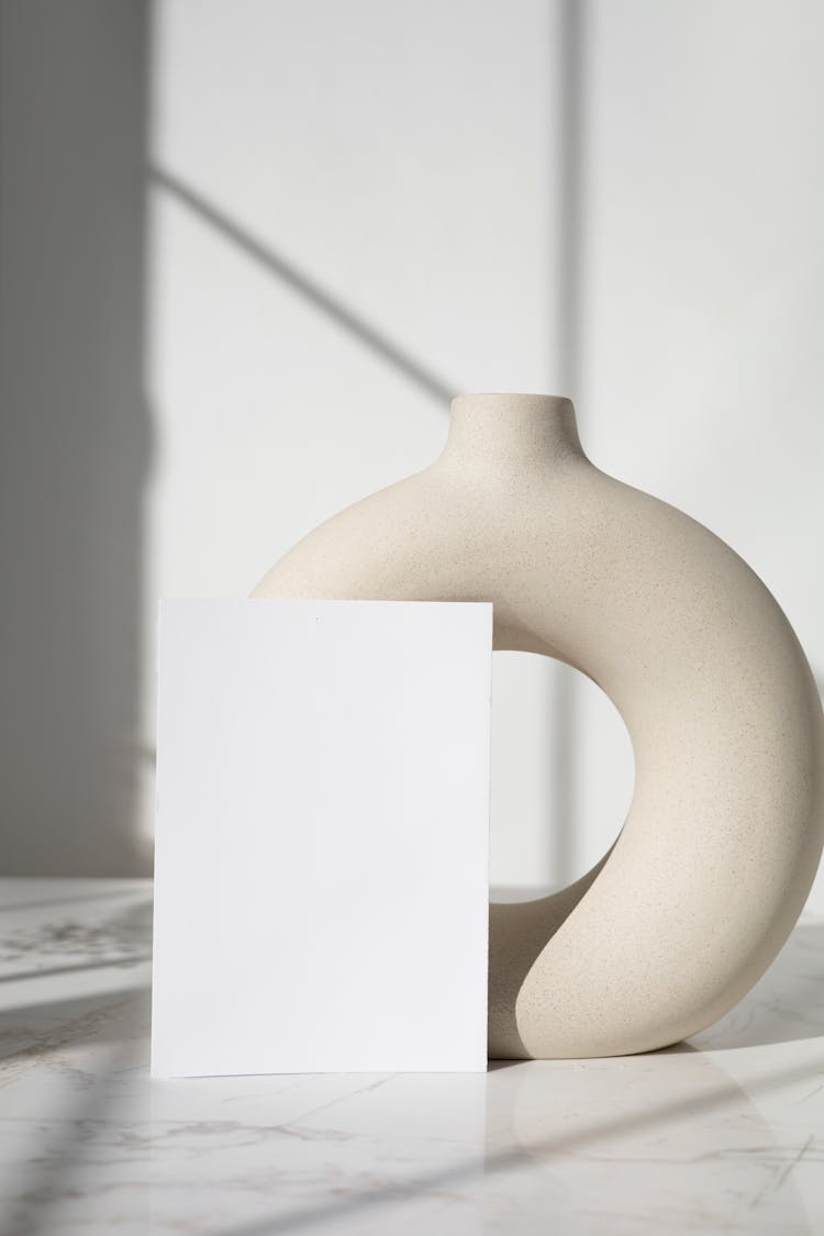 White Paper Beside A Nordic Ceramic Vase 