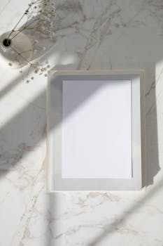 Elegant vertical mockup of a wooden frame on a marble background with soft shadows and white flowers.