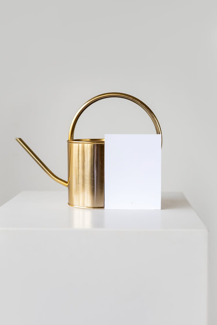 White Paper On A Gold Kettle On A White Table