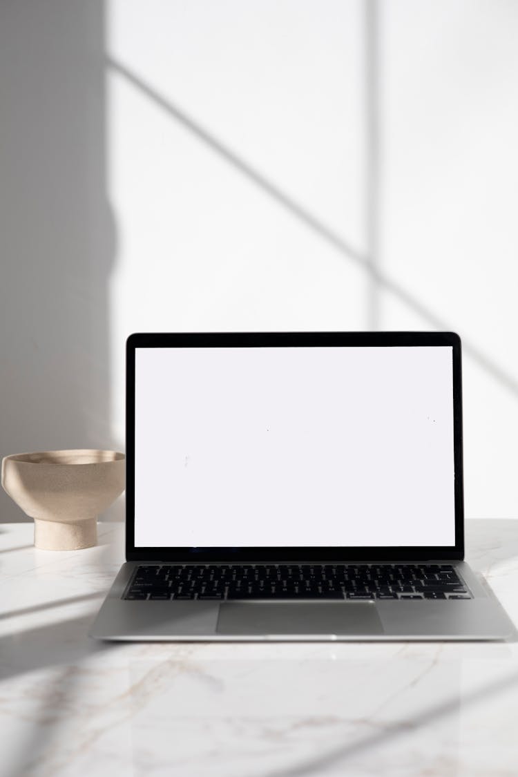 A Laptop With A Blank Screen On A Marble Surface