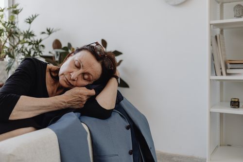 Free A senior woman in a black top resting on a couch in a minimalist room, conveying calmness and solitude. Stock Photo