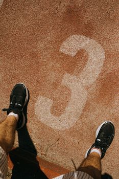 Top view of a person standing on lane three of an outdoor running track.