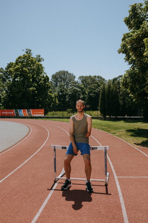 Portrait of an Athlete Posing on a Running Track with a Hurdle