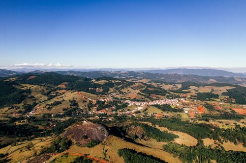 Free Aerial view of highland with hills covered with green trees and plants near settlement with buildings in countryside in daytime under blue cloudless sky Stock Photo
