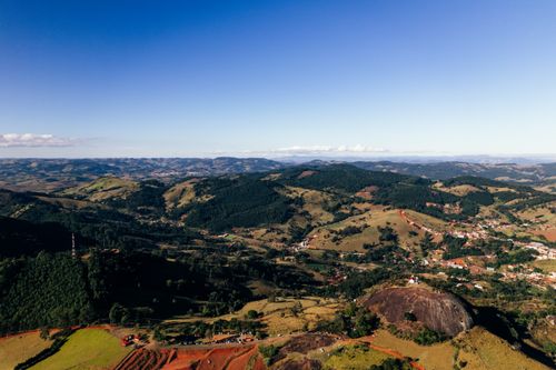 Free Drone view of landscape of small village in wild nature and breathtaking azure blue sky above mountains and green valleys Stock Photo