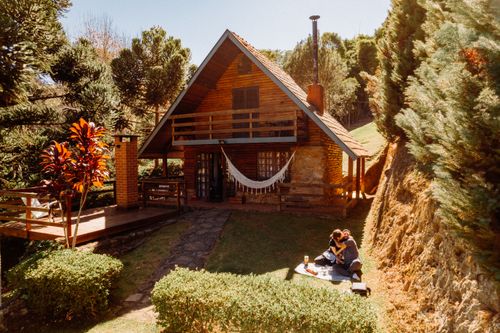 Free Couple enjoying a sunny picnic by a wooden cabin in São Bento do Sapucaí. Stock Photo