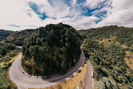 Gray Concrete Road Between Green Trees Under Blue Sky and White Clouds