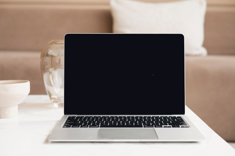 A modern laptop with a blank screen on a table in a cozy indoor environment