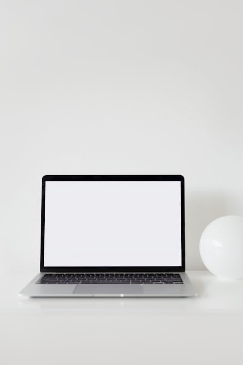 Free A Laptop with Blank Screen on a White Surface Stock Photo