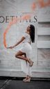 Woman in White Clothes and Heels Standing on One Leg