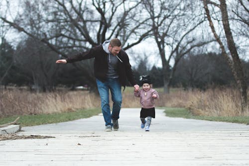 Free A Father and his Little Girl Running on a Park Pathway Stock Photo
