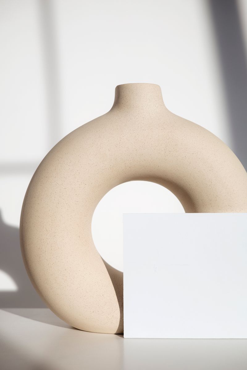 Round vase casting a soft shadow on a white plinth — photo by Hanna Pad on Pexels