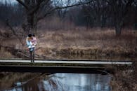 在宁静的森林中，一位母亲抱着她的孩子站在桥上