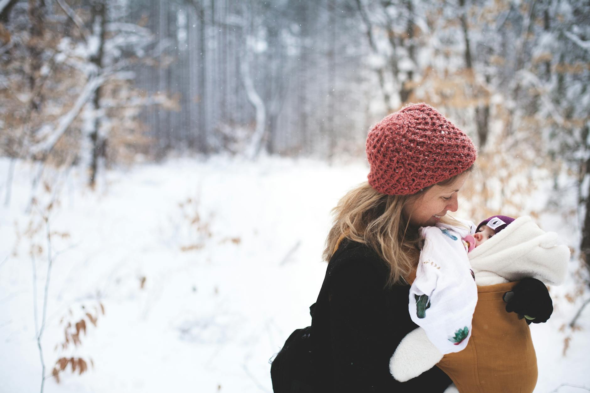 A mother and baby enjoying a winter day in a snowy forest, symbolizing love and warmth.