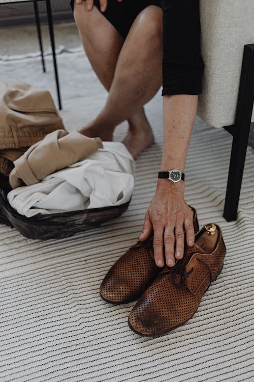 Hand of a Person on a Brown Leather Shoes