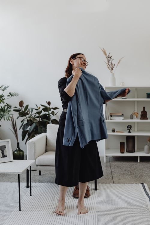 Free A woman holds a blue suit close in a modern living room setting, expressing emotion. Stock Photo