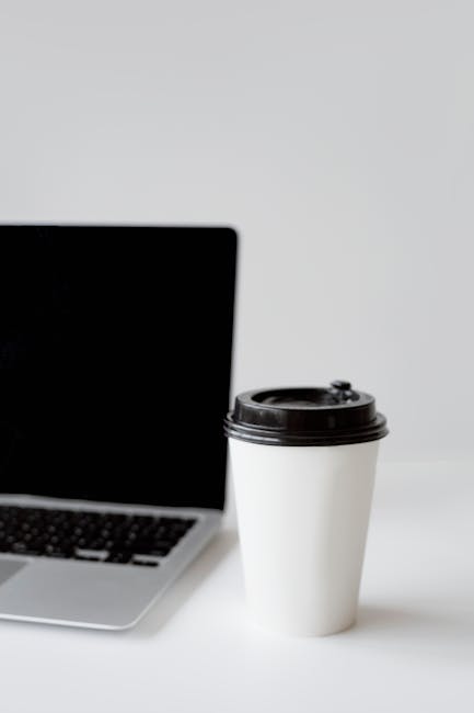 Black and Silver Laptop Computer Beside White and Black Tumbler