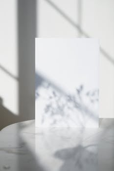 A minimalist vertical image featuring a blank paper with artistic light and shadow effects.