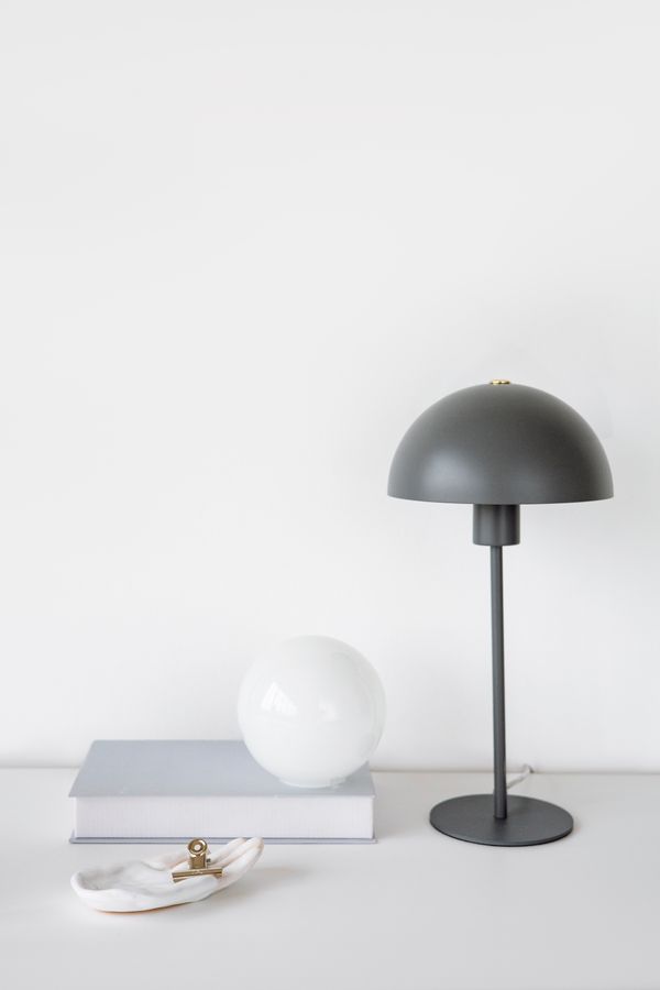 A domed table lamp and glass orb on a pale surface, photo by Hanna Pad on Pexels