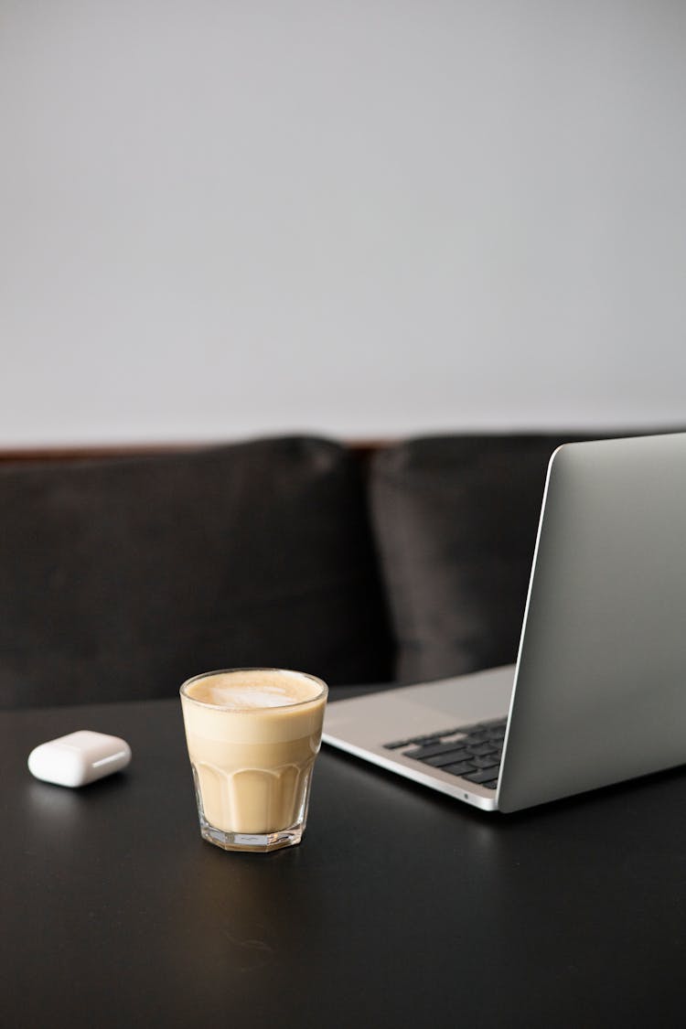 A Glass Of Coffee Beside A Laptop On A Desk