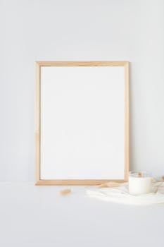 Simple minimalist mockup of a wooden frame and candle on a white surface, perfect for designs.