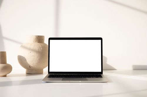 Free Modern minimalist workspace displaying a laptop with clay vases, emphasizing simplicity and style. Stock Photo