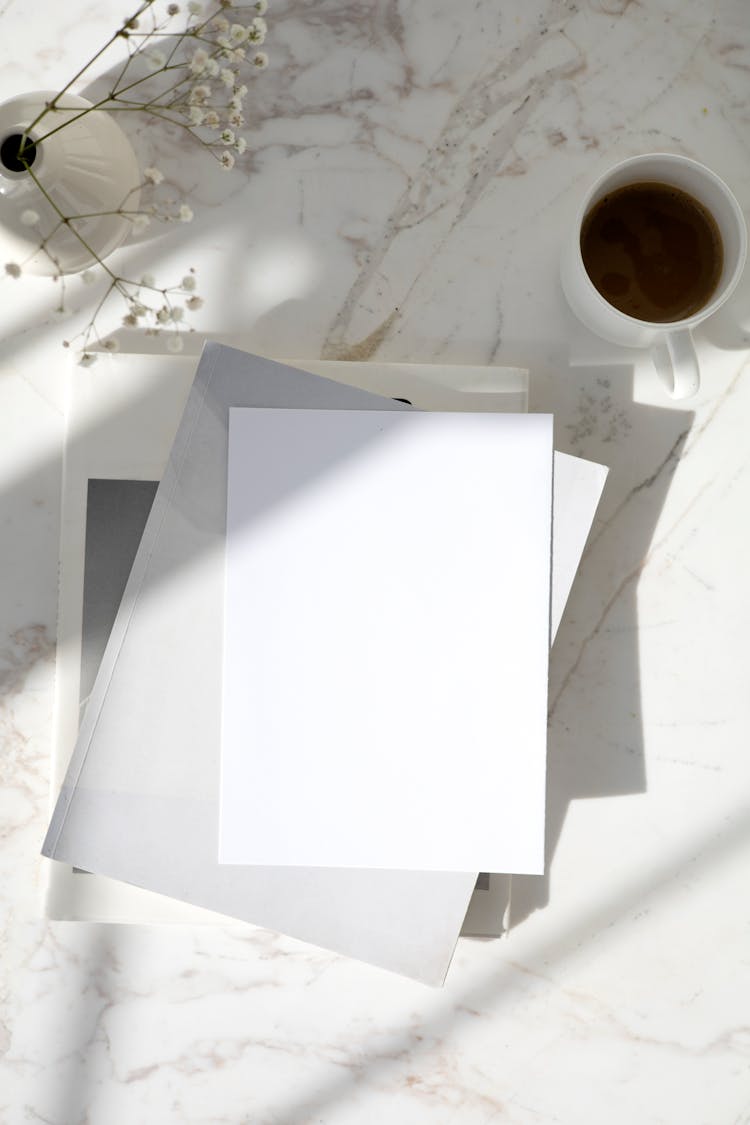 Stack Of Blank White Paper Sheets And A Cup Of Coffee On A Table