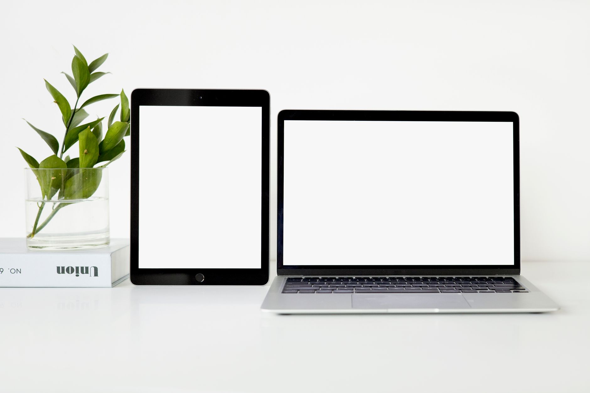 數位斷捨離:重新整理注意力,找回生活專注力 Modern minimalist workspace featuring a laptop and tablet on a white desk with green plant.