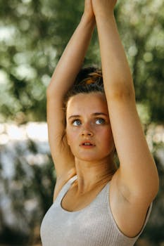 Caucasian woman performing yoga pose outdoors with arms raised, enhancing flexibility and mindfulness.