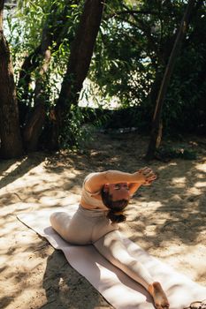 Woman practicing yoga outdoors on a sunny day surrounded by nature.