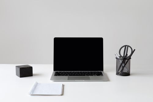 Free Modern minimalist workspace featuring a laptop, notebook, and stationery on a white surface. Stock Photo