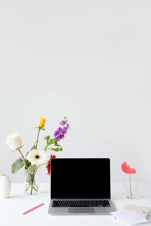 Free Gray Laptop near Flowers in Clear Glass with Liquid  Stock Photo