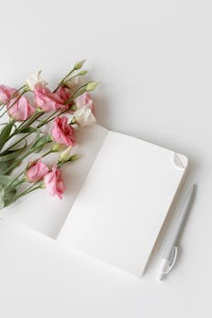 Open notebook with pink and white flowers and a pen. Perfect for minimalistic designs.