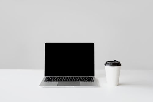 Free Photo of a Laptop Beside a White Paper Cup Stock Photo