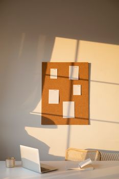 A serene workspace featuring a corkboard with notes, casting shadows in warm light. Perfect for productivity.