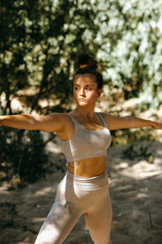 A young woman in a yoga pose outdoors, showcasing strength and focus in a summer setting.