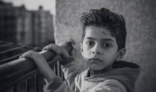 一张表情严肃的小男孩的黑白肖像在户外