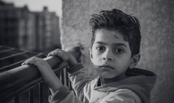 一张表情严肃的小男孩的黑白肖像在户外