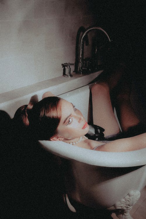 Portrait of a Woman Wearing Pearl Necklace Taking a Bath in a Vintage Style Bathtub