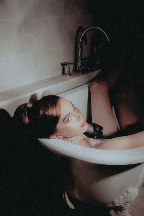 Free Portrait of a redhead woman in a bathtub, exuding vintage glamour and sensuality. Stock Photo