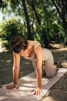 Woman in yoga pose on mat surrounded by nature, emphasizing outdoor fitness.