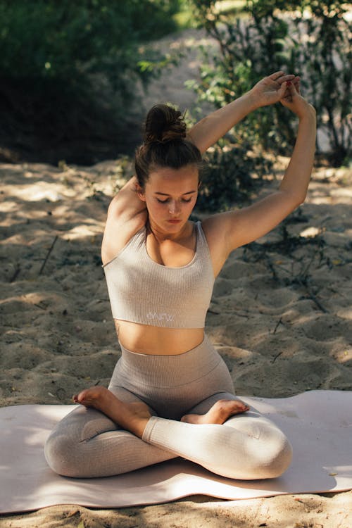 A Flexible Woman in Beige Activewear Stretching Her Arm