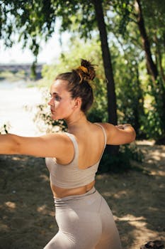 A young woman in sportswear practicing yoga outdoors, embracing a healthy lifestyle.